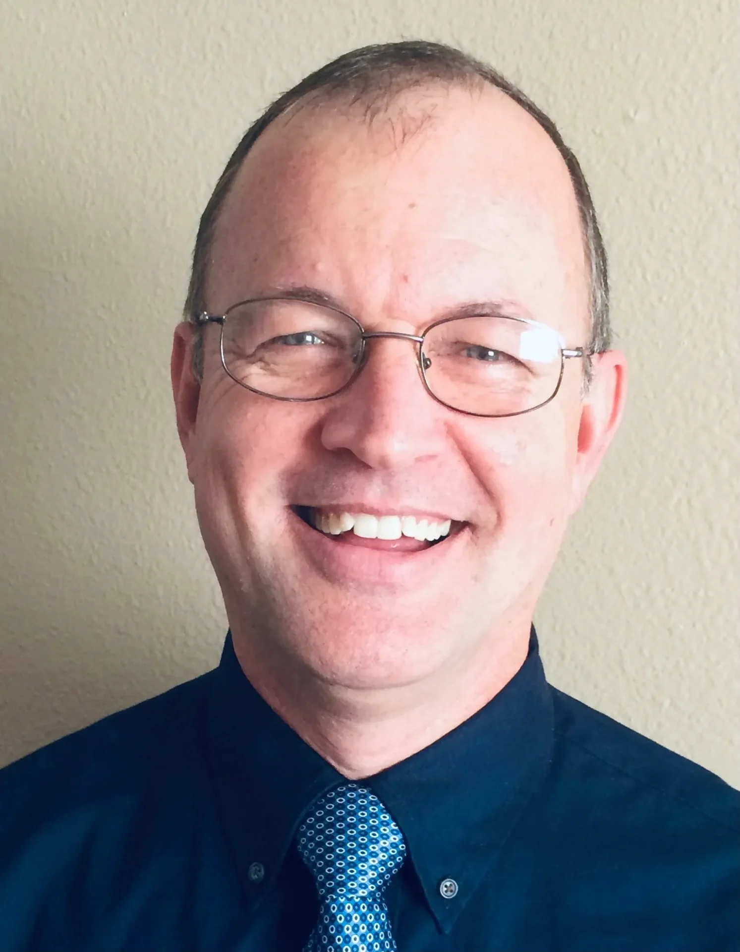 A man with glasses and a blue tie.