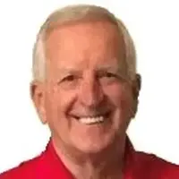 A man with white hair and wearing a red shirt.