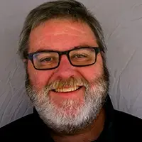 A man with glasses and beard smiling for the camera.