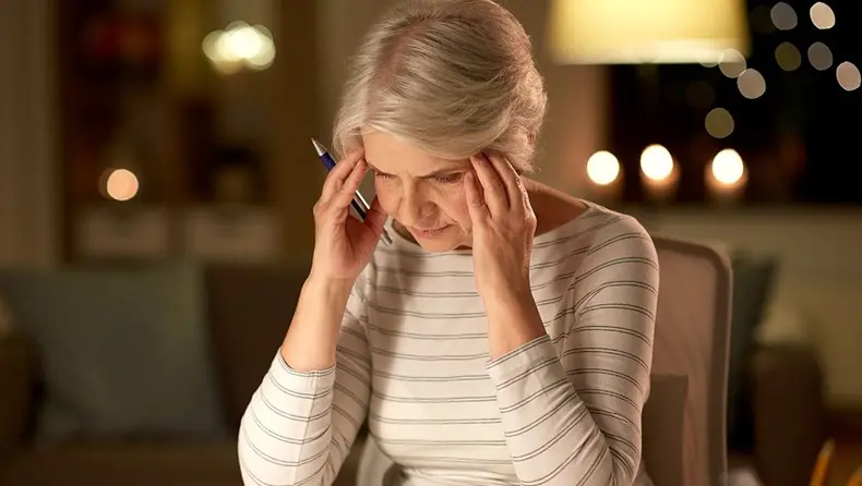 A woman holding her head while talking on the phone.