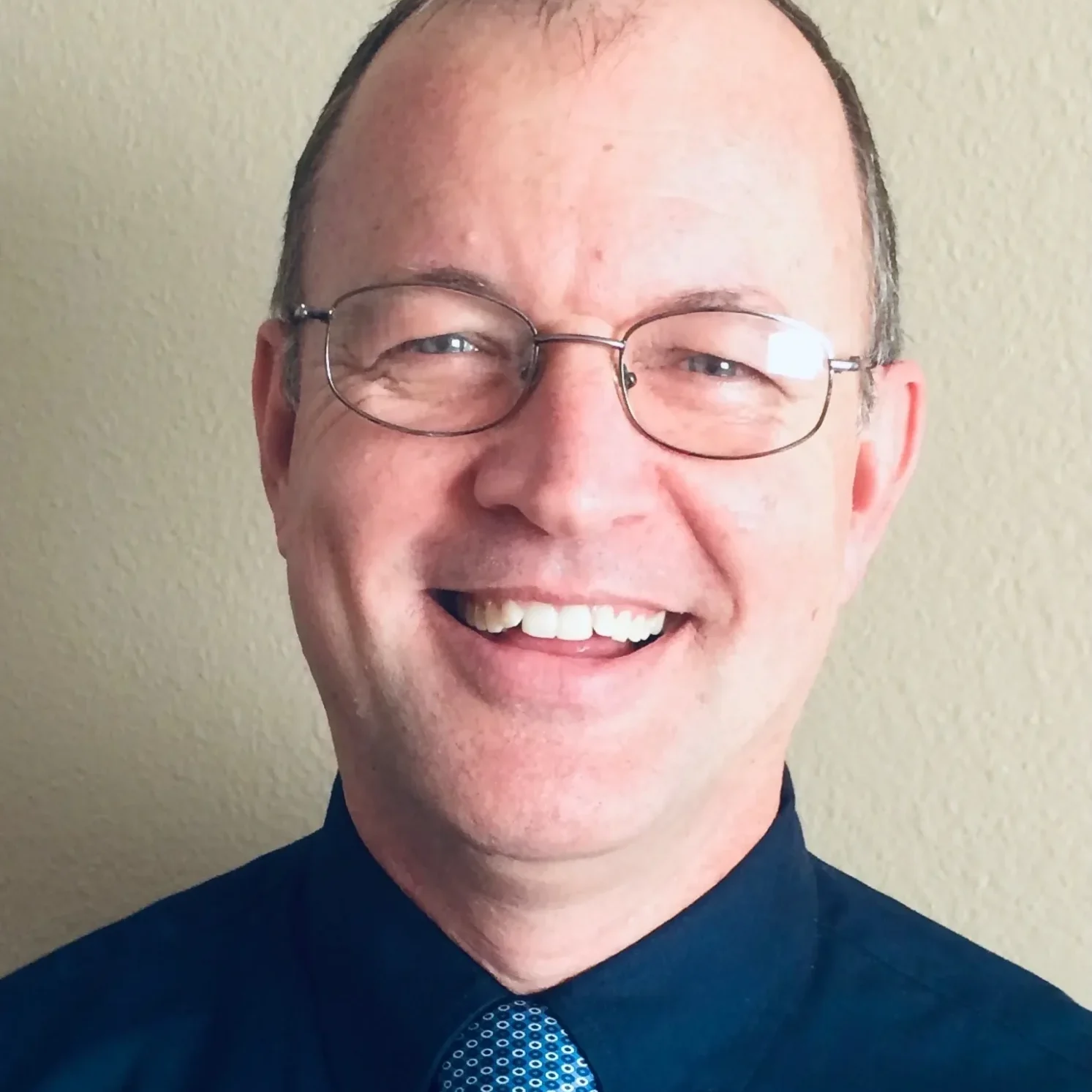 A man with glasses and a blue tie.